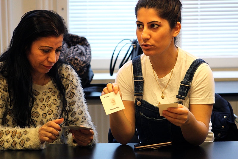 Hanan och Samira berättar för de övriga i gruppen vad de har för matvaror på sina kort och vad de kostar.