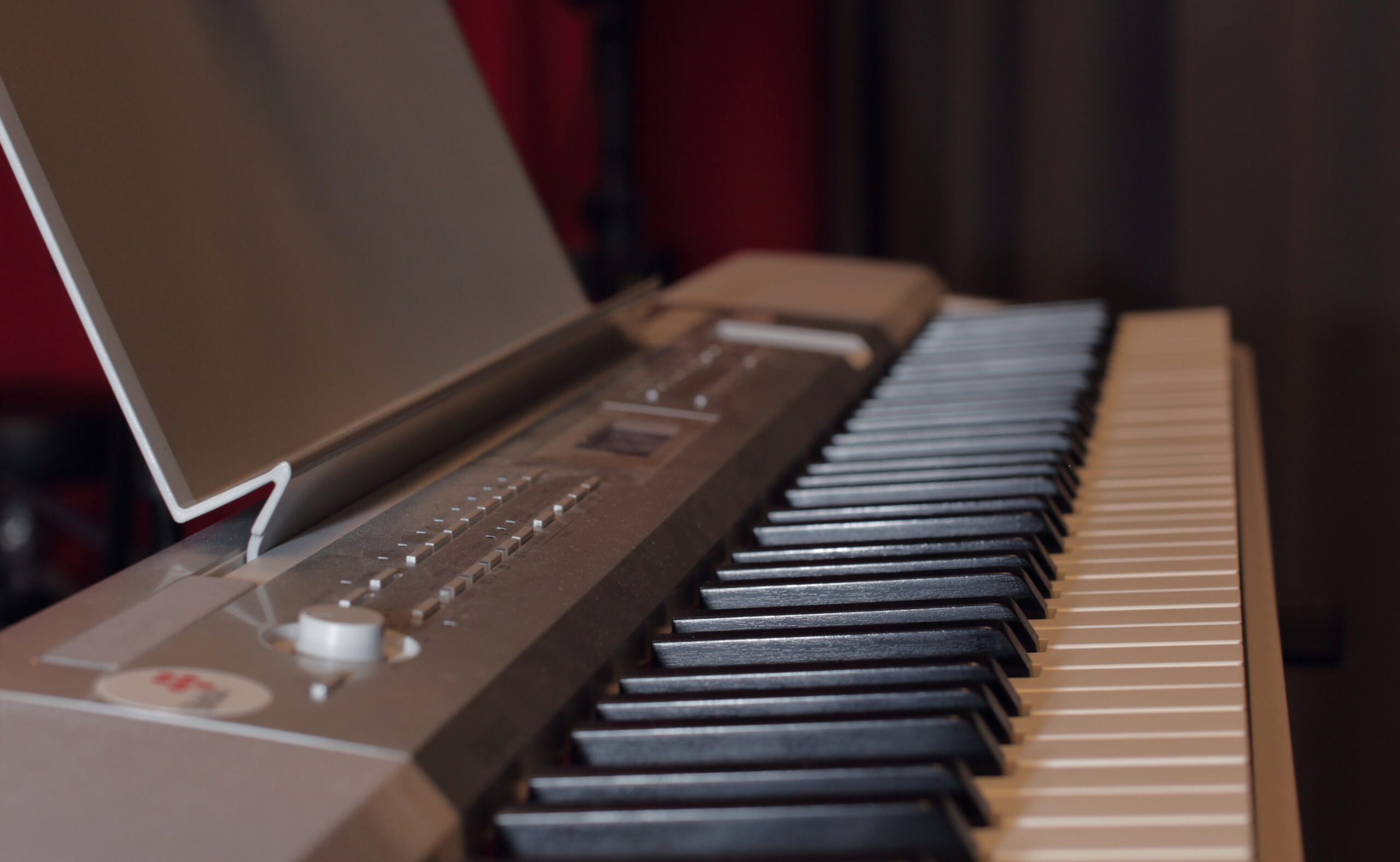 Närbild av ett digitalt keyboardpiano med svarta och vita tangenter i fokus och kontrollpanelen delvis synlig.