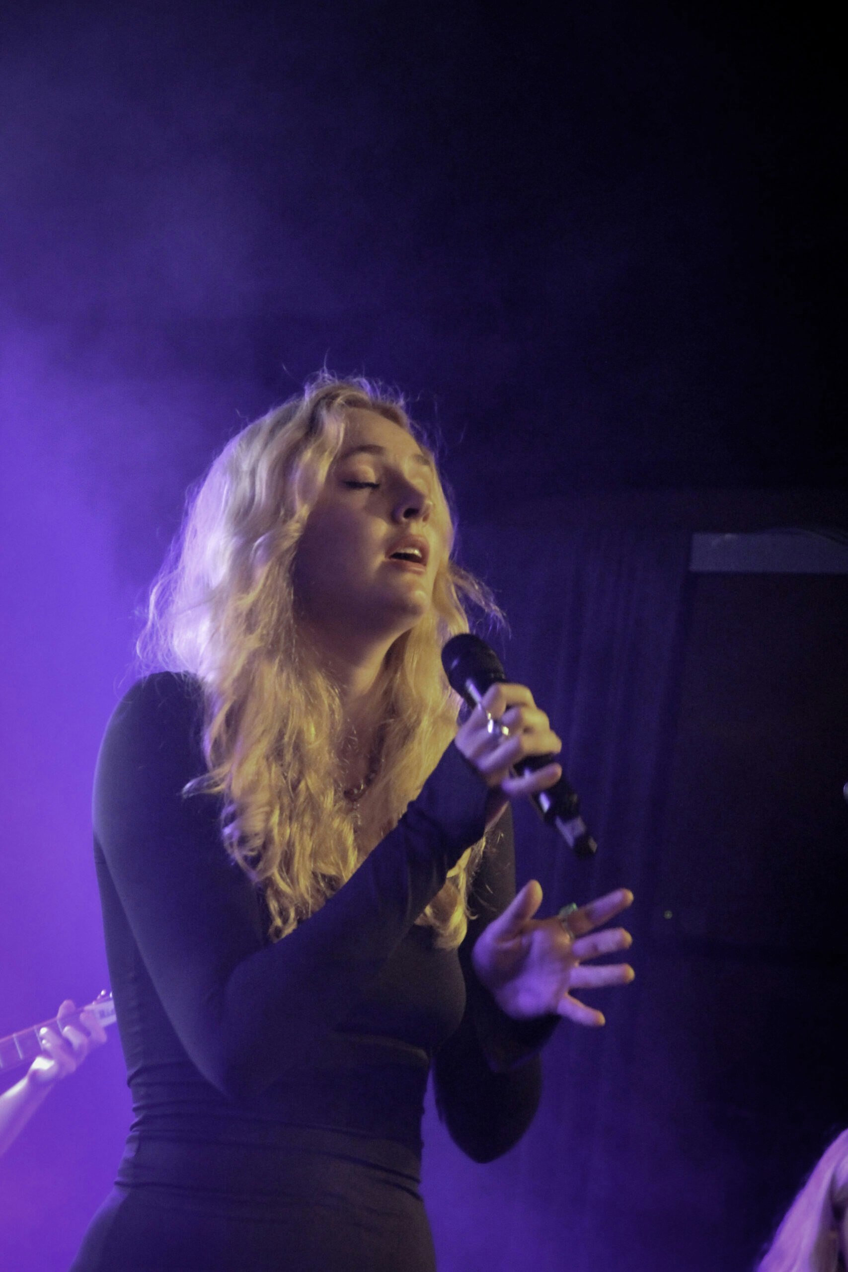 En kvinna som sjunger i en mikrofon på scenen.