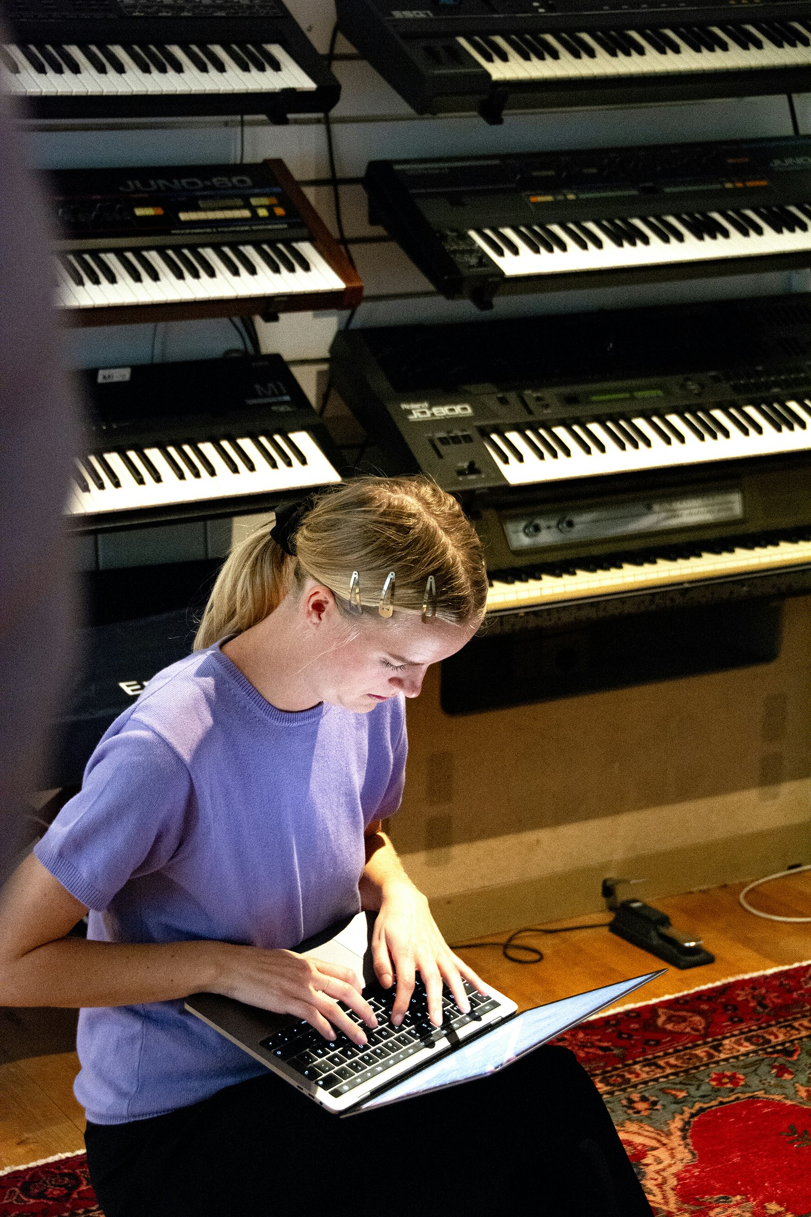 En kvinna som arbetar på en bärbar dator i ett rum fullt av musikinstrument.
