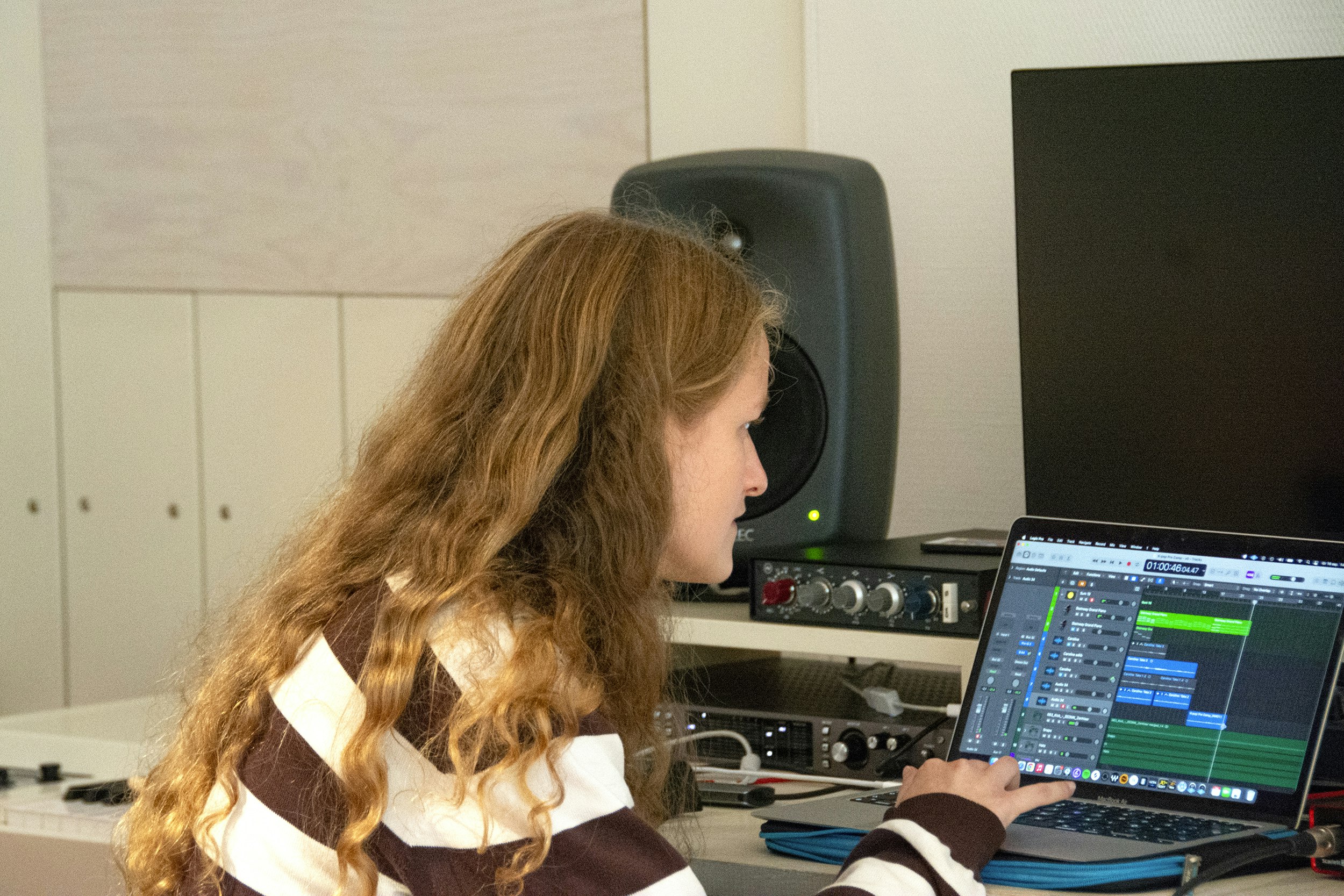 En flicka som arbetar på en bärbar dator i en inspelningsstudio.