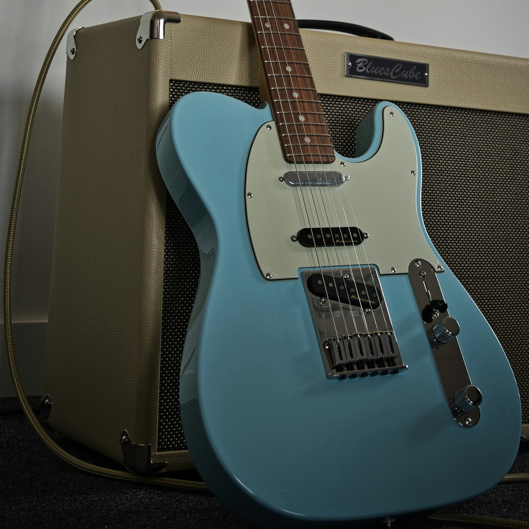 En blå elgitarr bredvid en blå förstärkare.