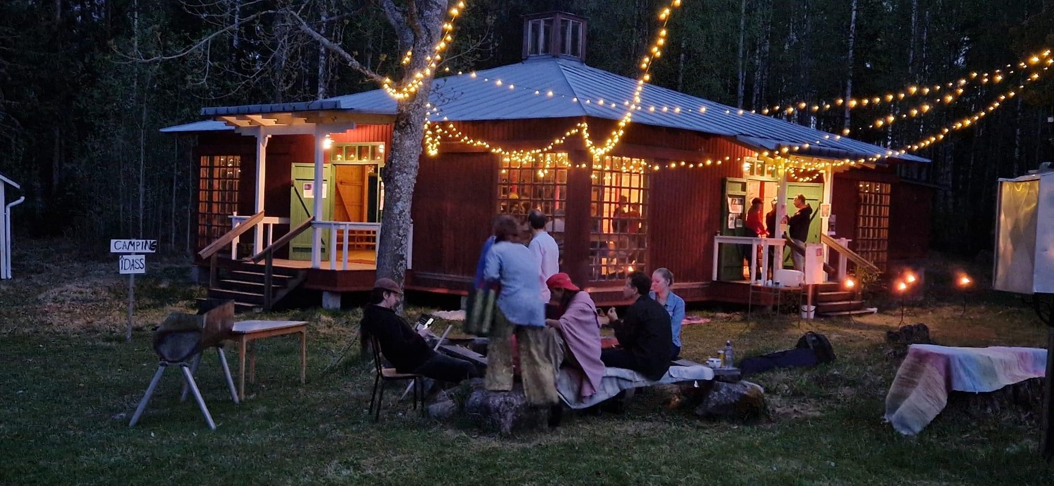 En grupp människor som sitter framför ett hus med ljusslingor.