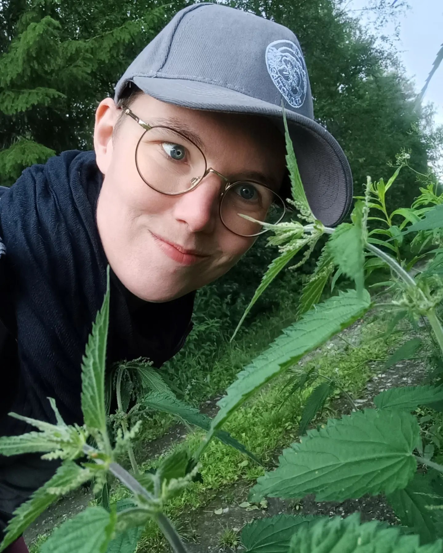 Person i keps vid brännäslor